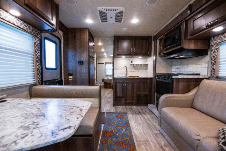 Spacious RV rental interior with a light-colored dinette, a full kitchen, and a comfortable couch.. Jayco Redhawk 2018