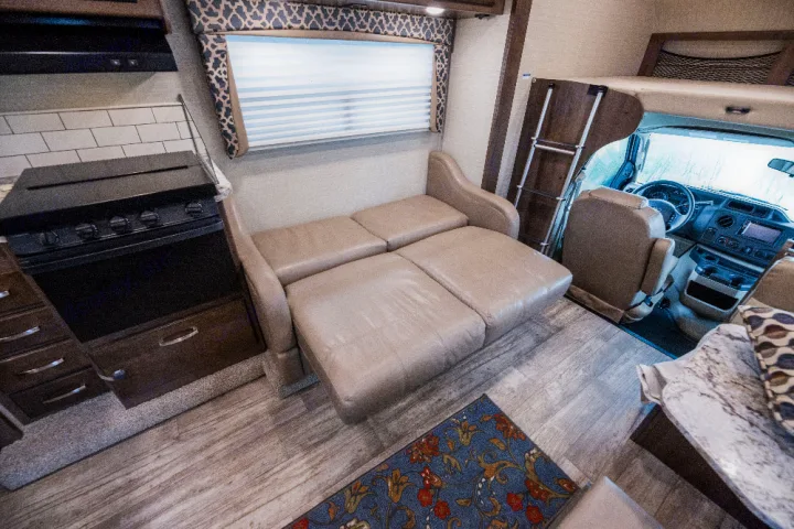 RV rental interior: kitchen, extended sofa, and cockpit visible, with over-cab bunk. Ready for trips.. Jayco Redhawk 2018