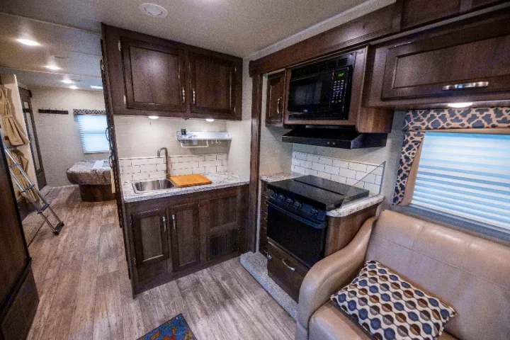 Spacious RV rental interior: modern kitchen, living area with sofa, & bedroom with bunk bed visible.. Jayco Redhawk 2018