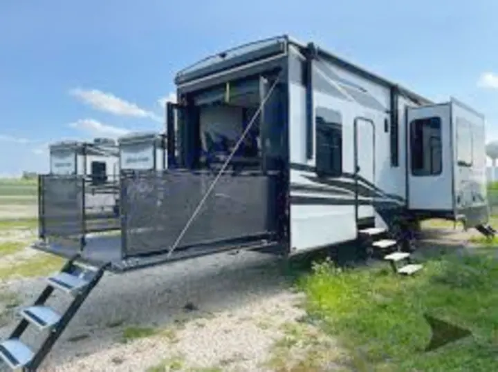 This white and black toy hauler RV rental, with its rear patio deck and steps extended, is perfect for camping adventures.. Grand Design Momentum 2024