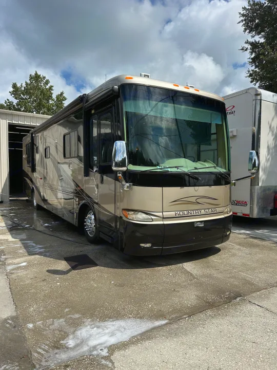 Large Kountry Star RV (possible RV rental) being washed outside a service bay. Soapy concrete on a cloudy day.. Kountry Star Kountry Star Motorhome 2008