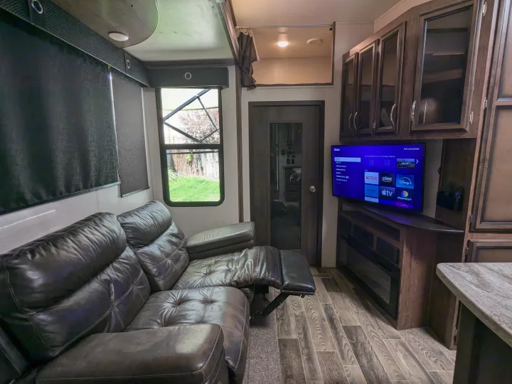 Relax in this comfy RV rental living area, featuring a reclining sofa, Roku TV, electric fireplace, and stylish interior.. K-Z Manufacturing Venom V3411TK 2020