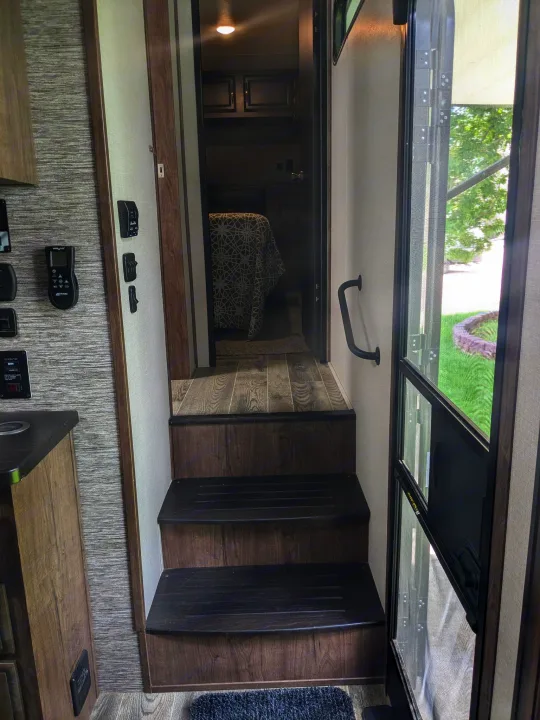 RV rental interior: Steps lead to the bedroom. Controls are on the left wall, entry door and screen on the right.. K-Z Manufacturing Venom V3411TK 2020