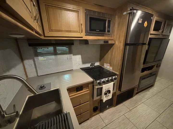 This RV rental boasts a modern kitchen, complete with a sink, microwave, stove, and refrigerator, offering essential amenities.. Forest River Palomino Solaire 2021