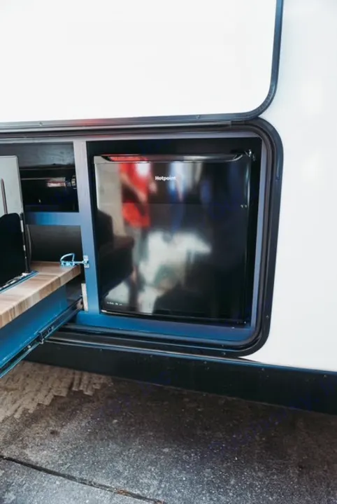 This RV rental features an exterior compartment with a Hotpoint mini-fridge and pull-out outdoor kitchen.. Forest River Tracer 2024