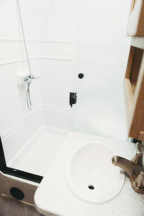 Compact RV rental bathroom: white shower stall with glass door, and vanity with a clean sink and faucet.. Forest River Tracer 2024