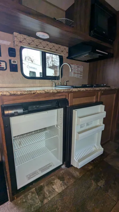 RV rental kitchen featuring an open fridge, stove, sink, counter, and microwave. Well-equipped for your travels.. Coachmen Viking 2017