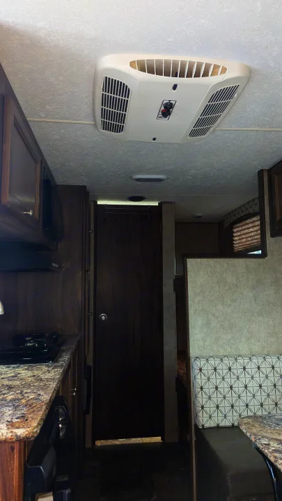 RV rental interior: kitchen with stove/microwave, dining booth seating, and overhead AC unit.. Coachmen Viking 2017