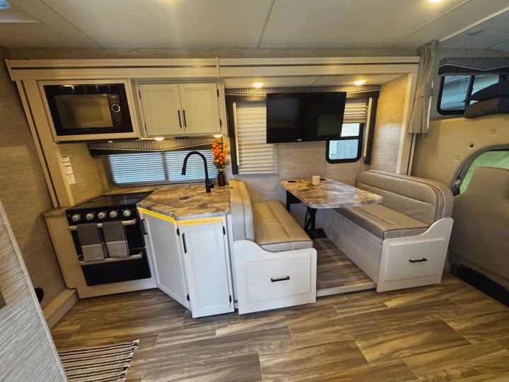 Cozy RV rental interior featuring a full kitchen, dinette, and TV, perfect for travel adventures.. Thor Motor Coach Four Winds 2022