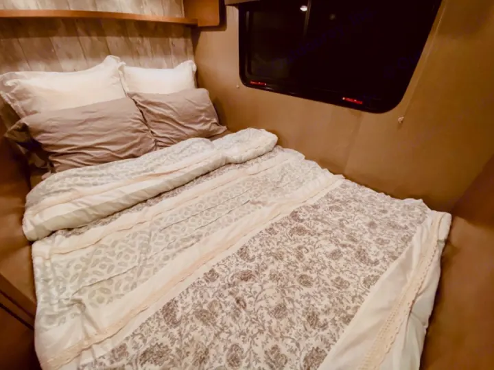 Inviting RV rental bed with plush pillows and a patterned comforter, offering comfort for your next adventure.. Winnebago 25 2019