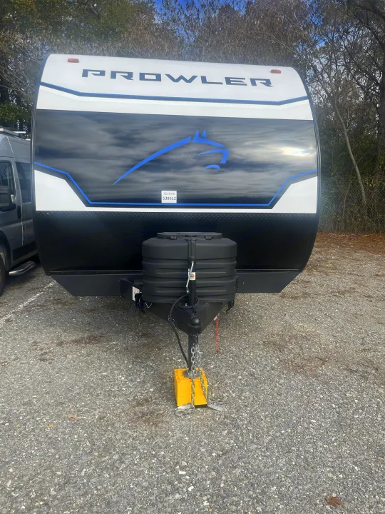 Front of a white & black Prowler 302BHX travel trailer for rv rental, showing its blue horse graphic & hitch.. Heartland RVs Prowler Lynx 302 BHX 2025