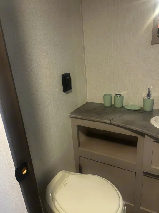 RV rental: Modern, compact bathroom with a toilet, vanity, light green accessories, and a wall-mounted outlet.. Heartland RVs Prowler Lynx 302 BHX 2025