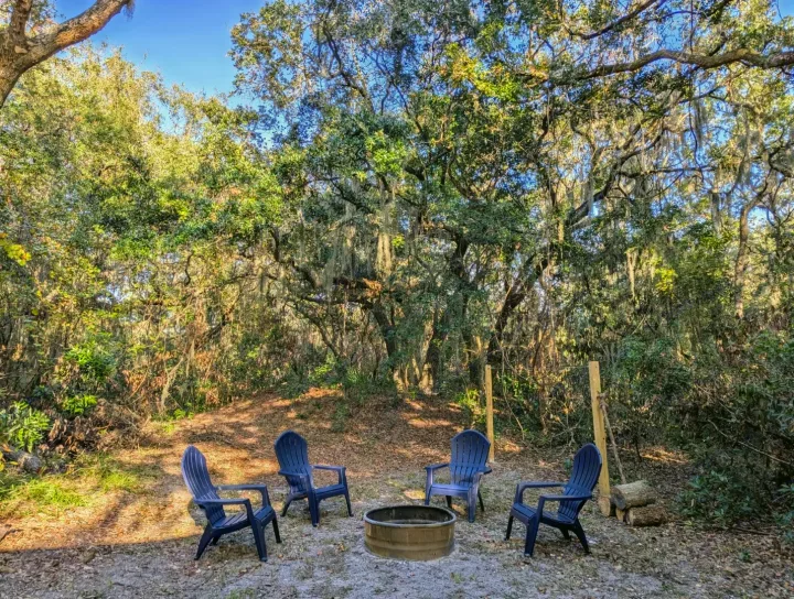 A cozy fire pit surrounded by four chairs in a serene, moss-draped forest; perfect for your RV rental escape.. Cruiser Rv Corp Other 2024