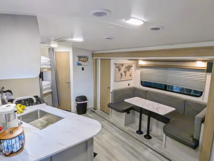 Inside a well-equipped RV rental: bright kitchen area, comfortable U-shaped dinette, and cozy bunk beds for travelers.. Cruiser Rv Corp Other 2024