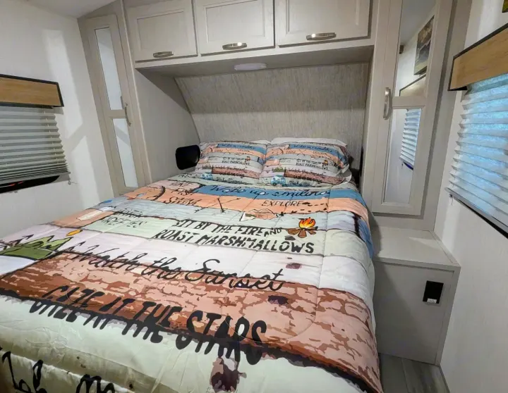 Cozy RV rental bedroom with an adventure-themed bedspread, overhead cabinets, and window blinds.. Cruiser Rv Corp Other 2024