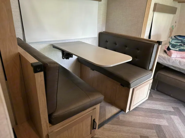 Cozy RV rental dinette featuring comfortable cushioned benches, a wall-mounted table, and under-seat storage.. Ember 191MBD 2022