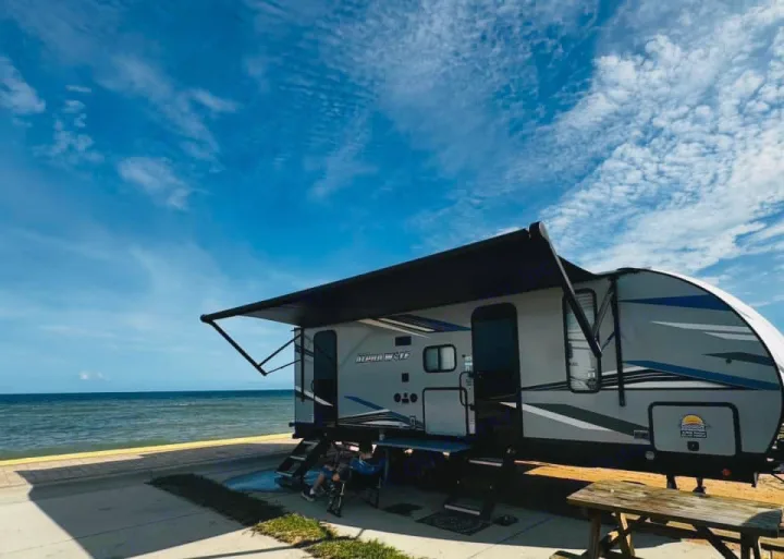 This Alpha Wolf RV rental with an extended awning offers a beachfront view of the ocean, perfect for a relaxing travel escape.. Forest River Cherokee Alpha Wolf 2022