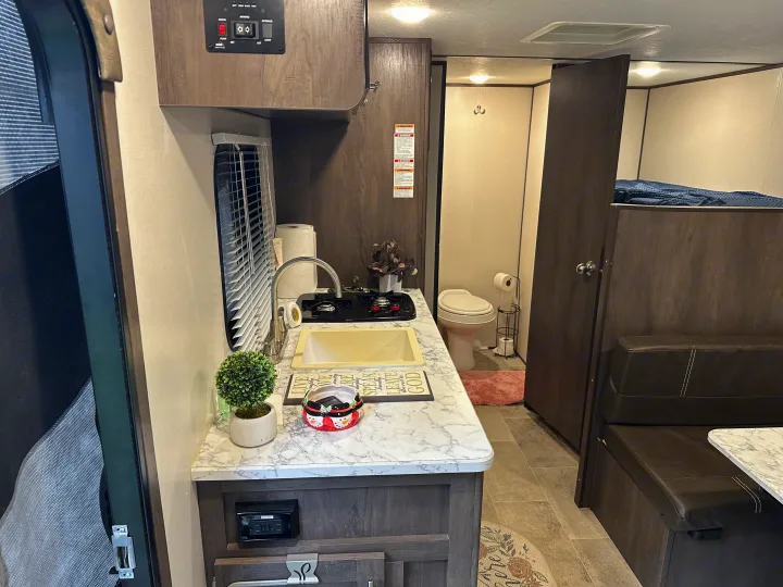 Cozy RV rental interior with kitchenette, bathroom, dinette, and bunk beds. Ideal for your next adventure!. Coleman 17b 2022