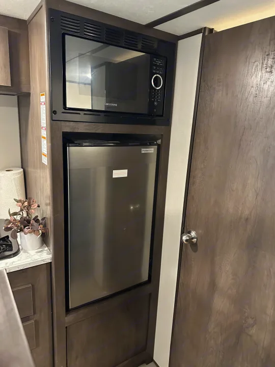 RV rental kitchen: Features a Greystone microwave and Ever Chill fridge integrated into compact cabinetry, ideal for travel.. Coleman 17b 2022
