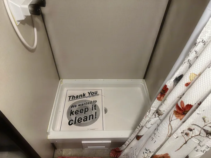 Clean RV rental shower with a "Thank You" sign. Features a white shower pan and a decorative shower curtain.. Coleman 17b 2022
