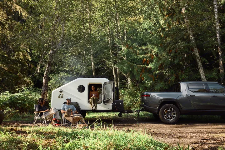 Friends enjoy their rv rental teardrop trailer & electric Rivian truck at a sunny forest campsite.. Campworks NS-1 Electrified 2024