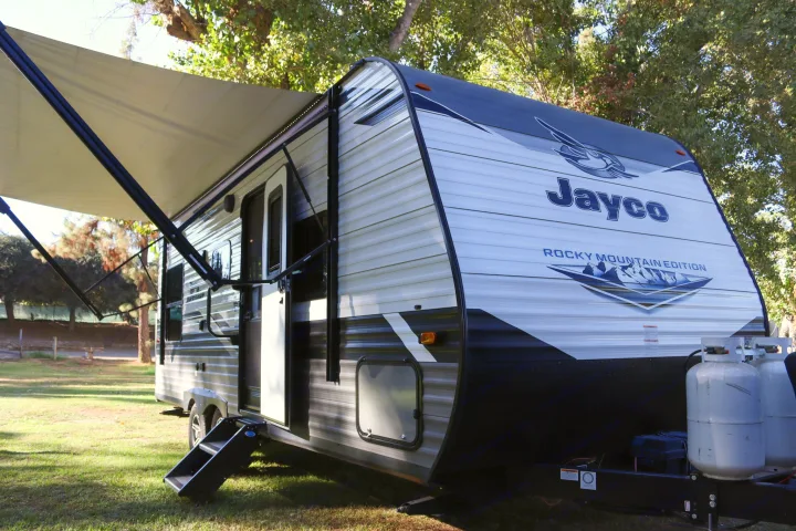 A white and black Jayco RV rental with its awning extended and steps down, parked on a grassy site. Ready for your camping trip.. Jayco Jay Flight SLX Rocky Mountain Edition 2022