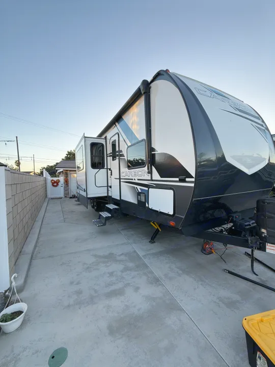 Large white/black "CARBON" RV rental travel trailer parked in a concrete driveway.. Keystone Carbon 2021