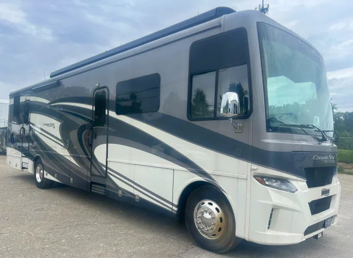 Exterior view of a grey and white Newmar Canyon Star diesel RV rental parked on gravel, perfect for your next road trip.. Newmar Canyon Star 2021