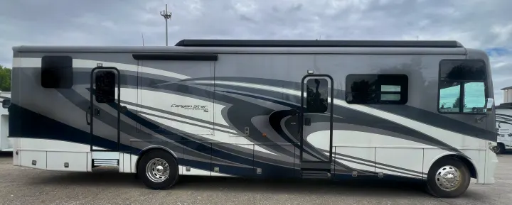 Large grey & white motorhome with swirl design. Ideal for your next RV rental, parked outdoors on a gravel lot.. Newmar Canyon Star 2021