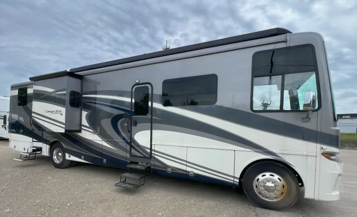 Spacious Class A RV rental: A sleek gray & white Canyon Star motorhome with extended slide-out and steps, parked on gravel.. Newmar Canyon Star 2021