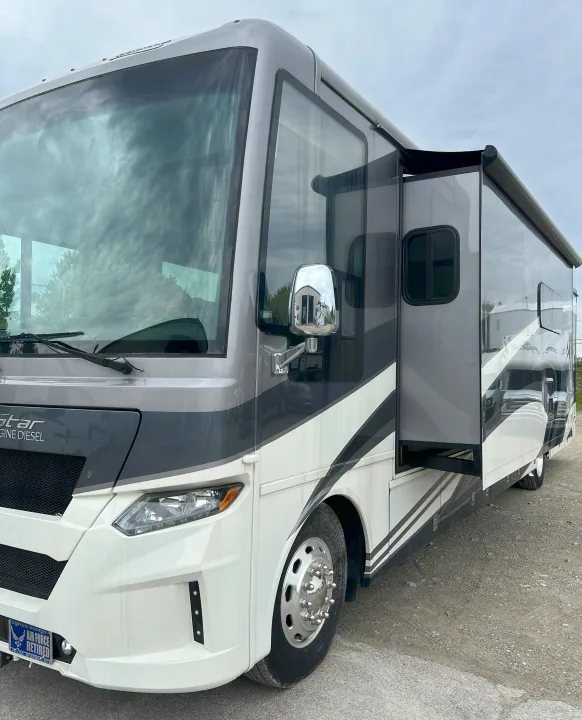 Grey & white Newmar New Star RV motorhome with extended slide-out, parked on gravel. Ready for an rv rental adventure.. Newmar Canyon Star 2021
