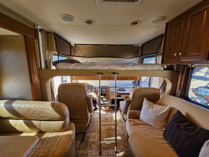 Spacious RV rental interior featuring an overhead bunk bed, front cockpit, and comfortable living areas. Perfect for adventures!. Thor Palazzo 2013