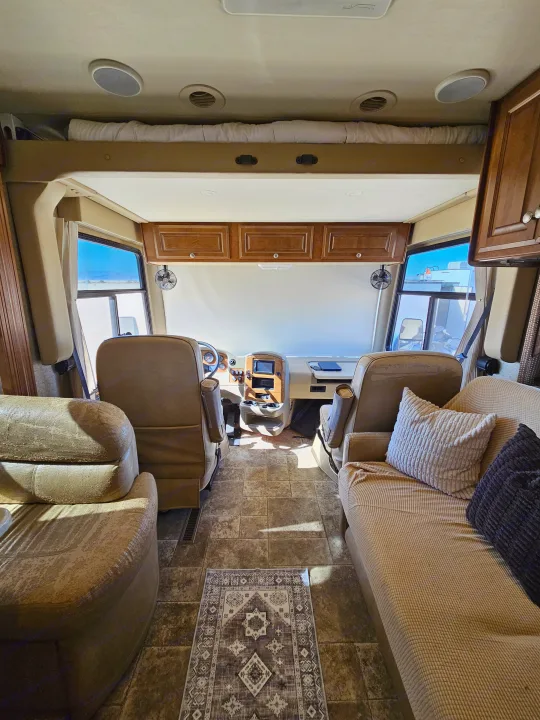 Spacious RV rental interior with inviting cockpit, comfortable living area, and overhead bunk. Perfect for road trips.. Thor Palazzo 2013