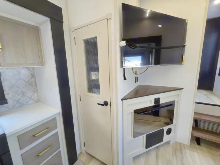 Step inside this modern RV rental's living area, showcasing a kitchen, private door, corner TV, and electric fireplace.. Forest River Hemisphere 2025