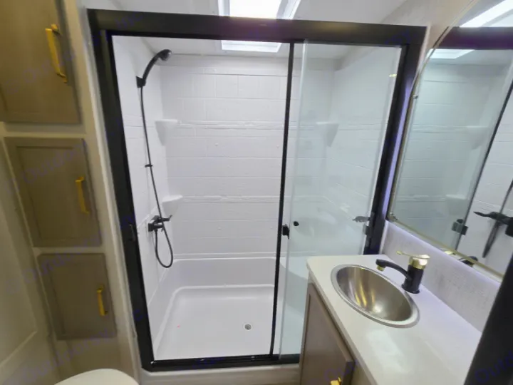 Compact modern RV rental bathroom featuring a shower with glass doors, a vanity with a sink, and cabinet storage.. Forest River Hemisphere 2025
