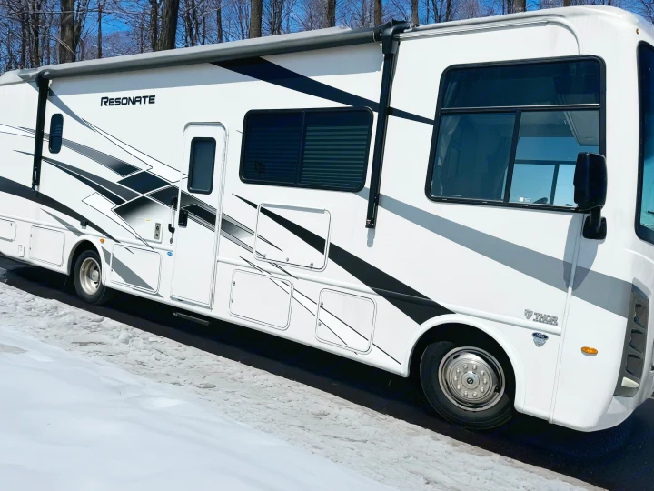 White Resonate RV rental, a Thor Motor Coach, with black/gray graphics, parked on a snow-covered path.. Thor Resonate 2024