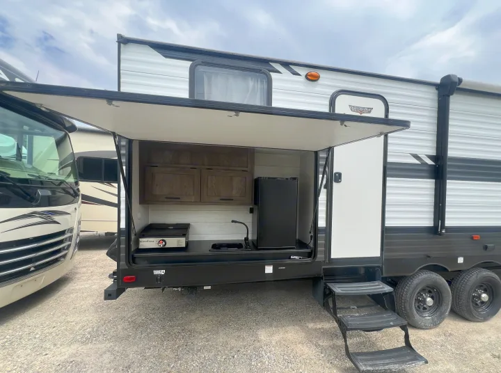 View this RV rental travel trailer with an outdoor kitchen, sink, griddle, and refrigerator setup.. Forest River Wildwood 2021