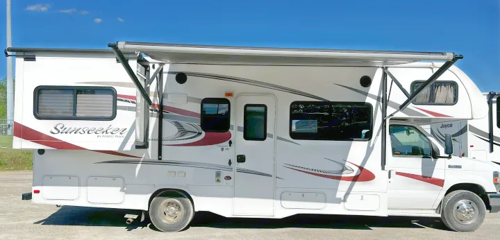 White Forest River Sunseeker RV rental with an extended slide-out and deployed awning, parked outdoors.. Forest River Sunseeker 2016