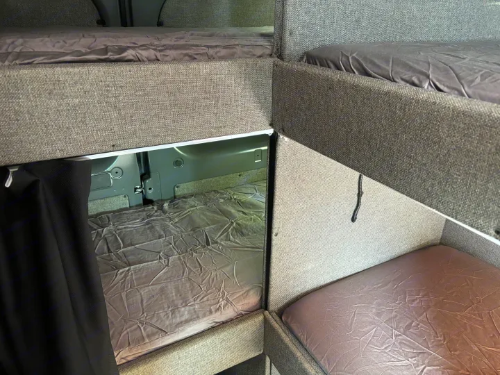 Inside an RV rental: multiple bunk beds with grey sheets, maximizing sleeping space in a compact camper van.. Dodge Sprinter Van 2024