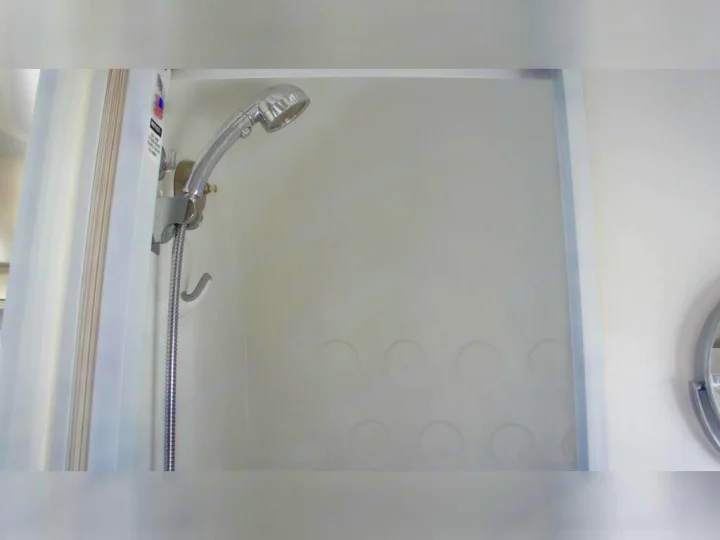 Compact shower in an RV rental, featuring a handheld showerhead and clean white interior, perfect for travel convenience.. Airstream Airstream 2020