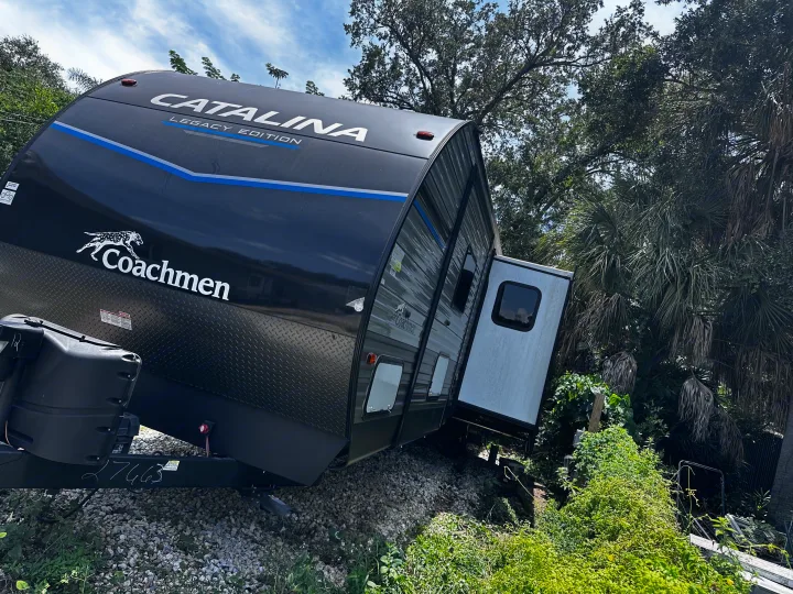 Coachmen Catalina Legacy Edition rv rental tilted by lush vegetation, showing an unusual parking or incident scene.. Coachmen 343bhts 2023