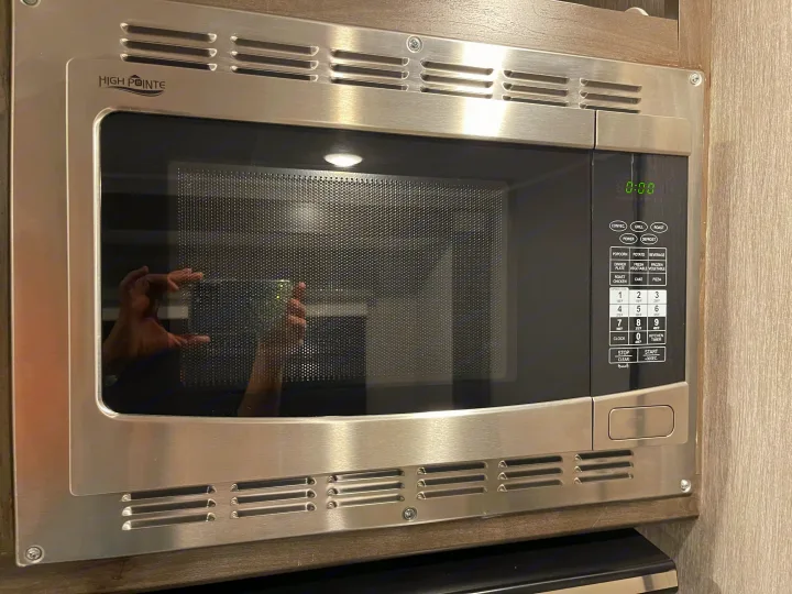 Stainless steel High Pointe microwave, built into an RV rental kitchen, with a digital display and detailed control panel.. Forest River Coachmen Leprechaun Premier 2022