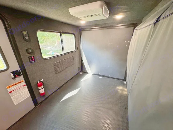 This RV rental's toy hauler garage features a durable floor, AC, windows, and safety equipment like a fire extinguisher.. InTech RV Flyer 2023