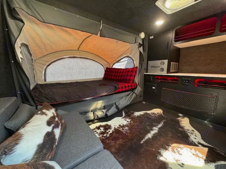 Cozy RV rental interior with pop-out bed, modern kitchenette, and stylish cowhide rug. Ready for adventure!. InTech RV Flyer 2023