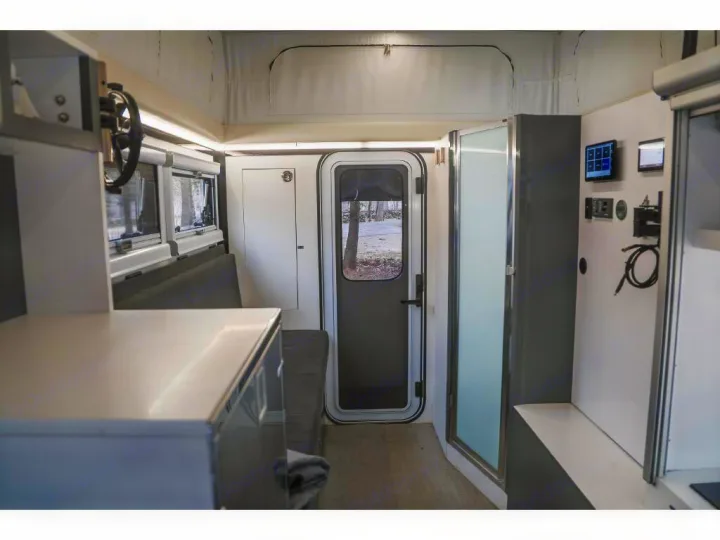 Inside a functional RV rental: modern layout with counter, windows, bench seating, main door, shower stall, and tech control panel.. Bruder EXP-6 2018