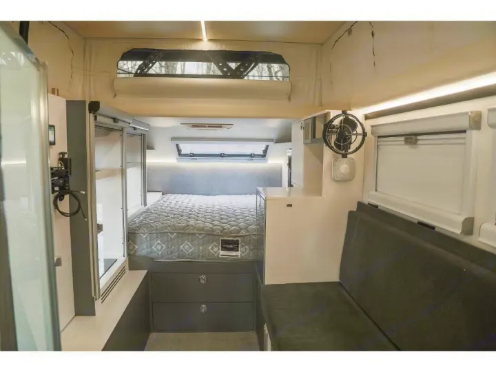 Modern RV rental interior with a comfy bed, storage, fan, and seating. Ideal for compact travel adventures.. Bruder EXP-6 2018
