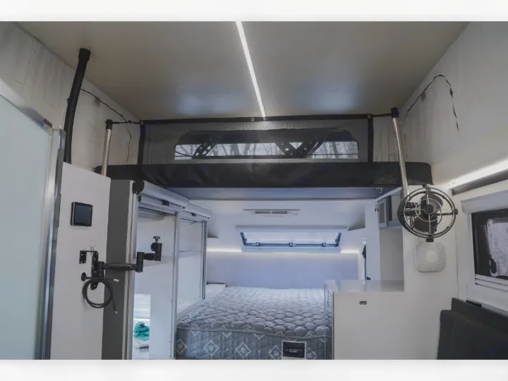 Inside an RV rental: A bright, modern interior featuring a lower bed, an upper bunk bed with netting, and white cabinetry.. Bruder EXP-6 2018