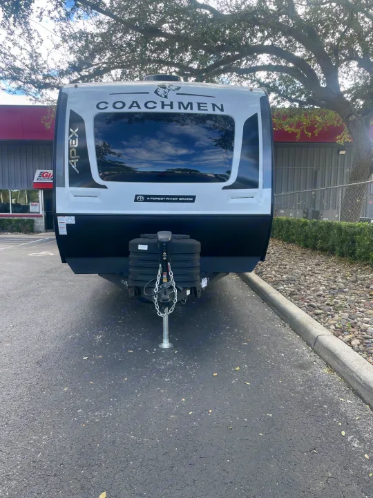 A modern Coachmen Apex travel trailer with a large reflective front window, available for RV rental.. Coachmen APEX 284BHSS 2025