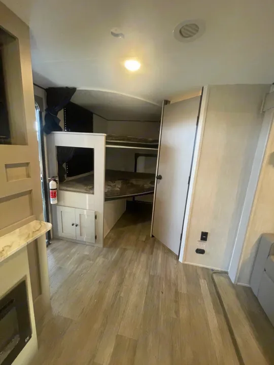 Explore this RV rental's modern interior: a bright living area with bunk beds, wood flooring, and practical features.. Coachmen APEX 284BHSS 2025