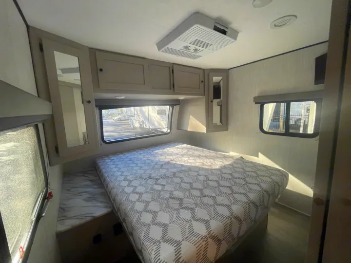 RV rental bedroom interior: cozy bed, overhead cabinets, AC unit. Ideal for comfort.. Coachmen APEX 284BHSS 2025